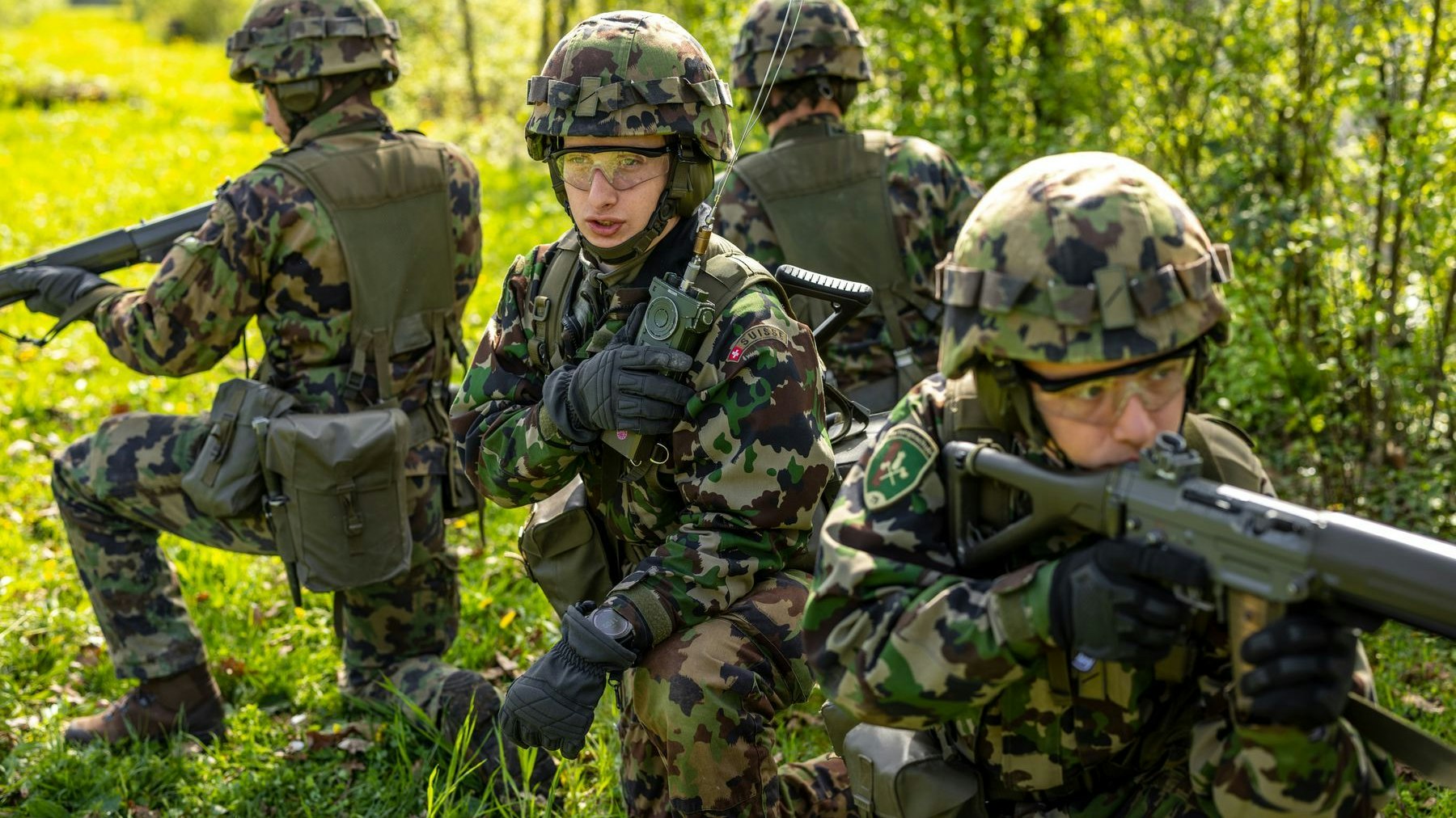 Mehrere Soldaten, die in einem offenen, bewaldeten Gebiet positioniert sind. 