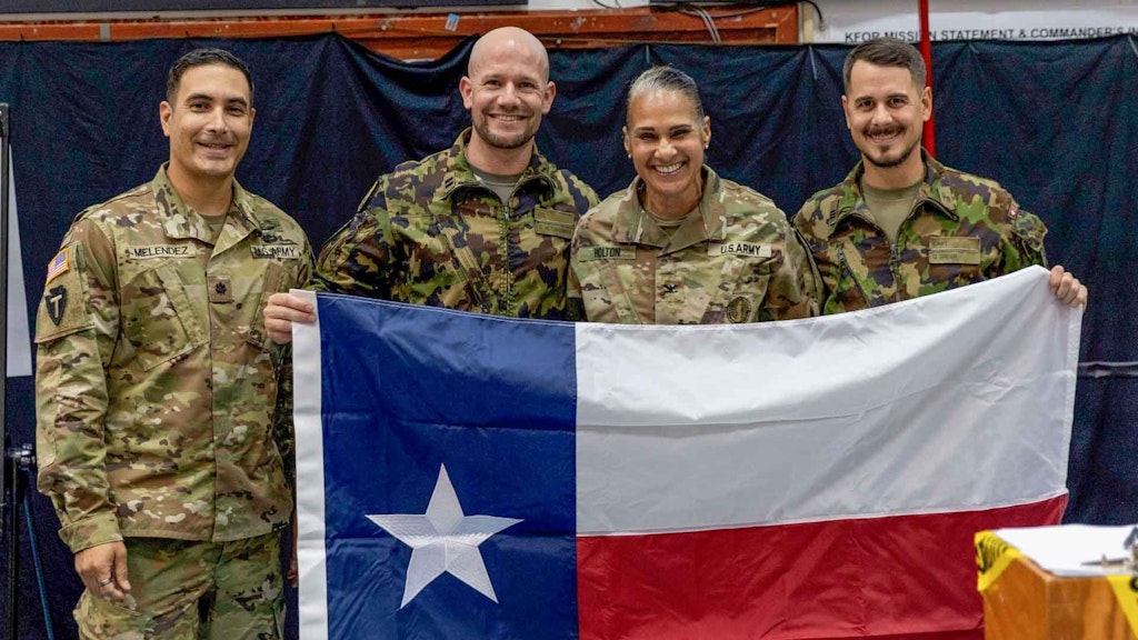 Major i Gst Christian Hiltbrunner (zweiter von links) leistete im Rahmen der SWISSCOY einen sechs- monatigen Einsatz als Chief Tactical Effects Centre im US-Brigadestab der KFOR. Da es sich um eine texanische Brigade handelte, hält er zusammen mit seinen Teamkolleginnen und -kollegen die Flagge des texanischen Bundesstaates.