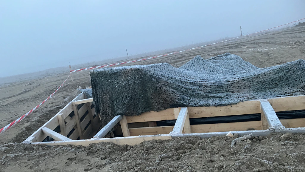 Schützengraben mit Tarnnetzen.