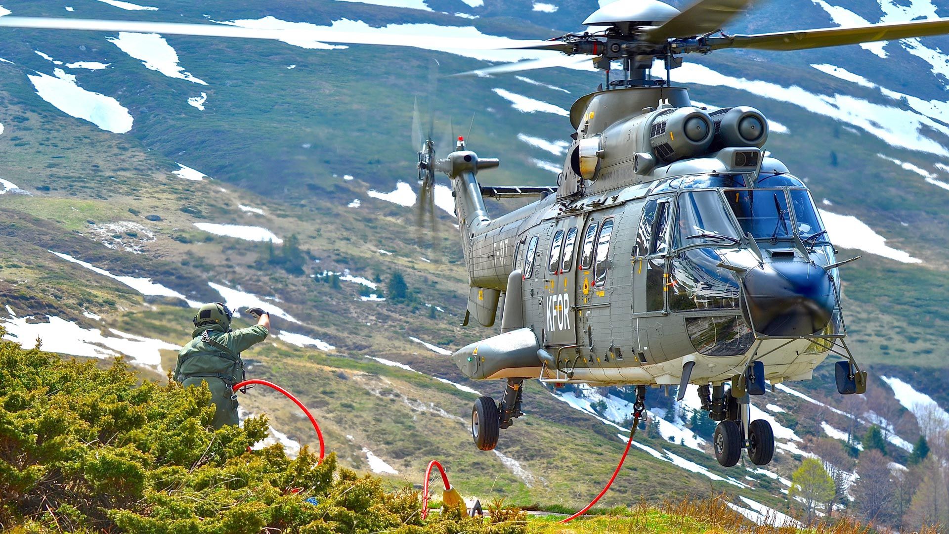 Au Kosovo, le loadmaster guide l’hélicoptère pour accrocher l’élingue destinée aux travaux d’héliportage qui vont suivre.