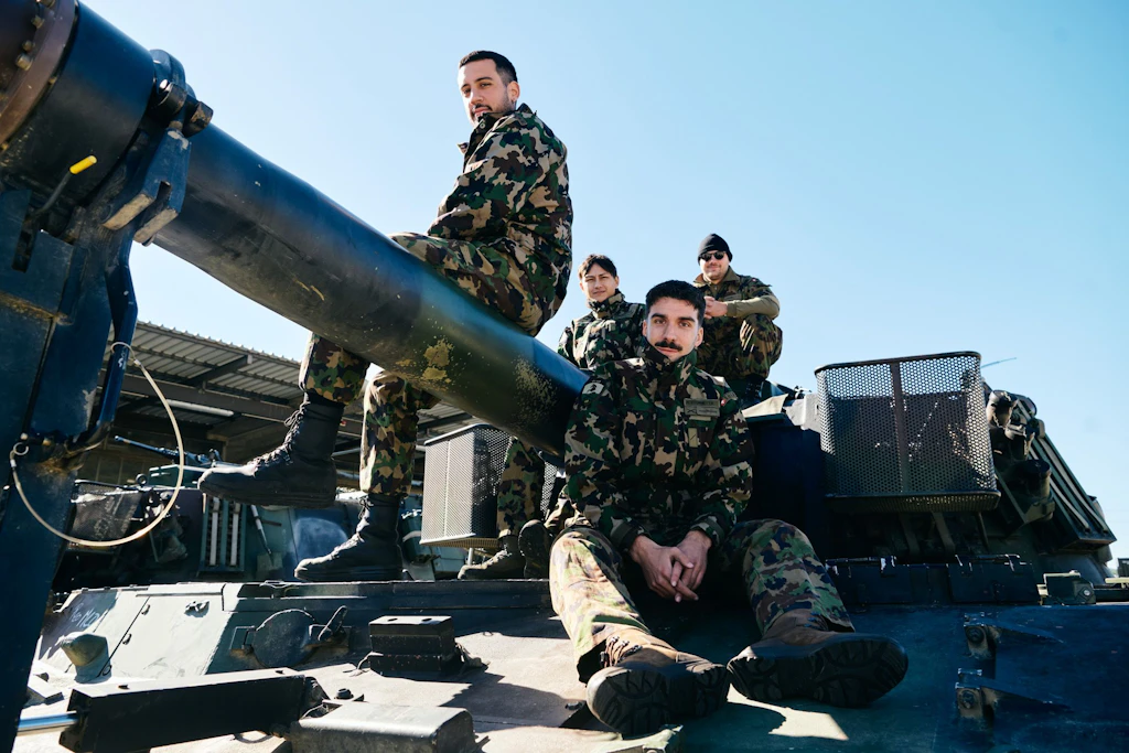 Quattro militari del gruppo d’artiglieria 49 siedono su un obice blindato M109, accanto alla canna.