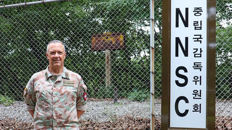 Il divisionario Ivo Burgener è il capo della delegazione svizzera della NSCC in Corea del Sud. Il team composto da cinque persone è stazionato nel Camp Panmunjom, ubicato lungo la linea di demarcazione militare tra la Corea del Sud e la Corea del Nord.