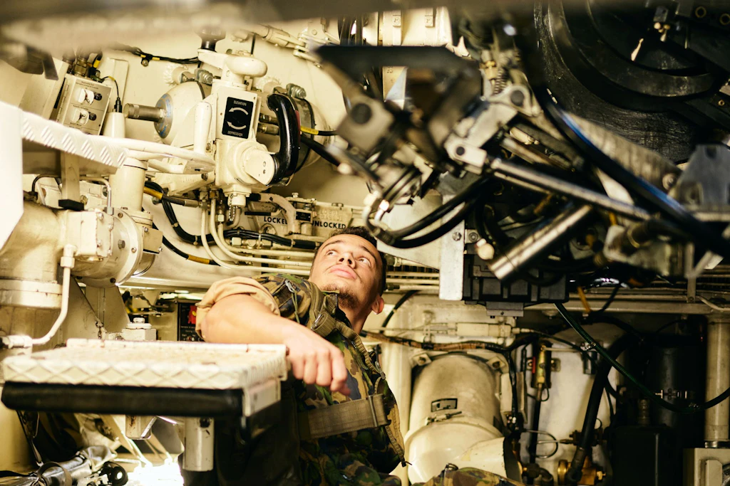Un militare controlla componenti tecnici e comandi nello spazio ristretto all’interno di un obice blindato M109.
