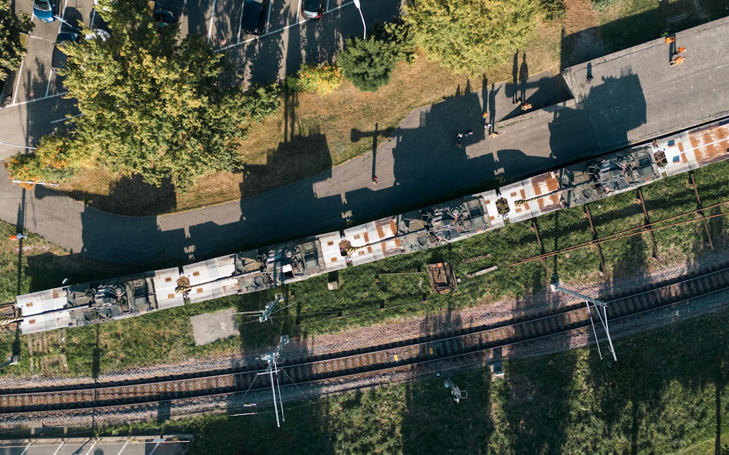Veduta aerea di diversi obici blindati M109 caricati su carri ferroviari lungo una stazione.